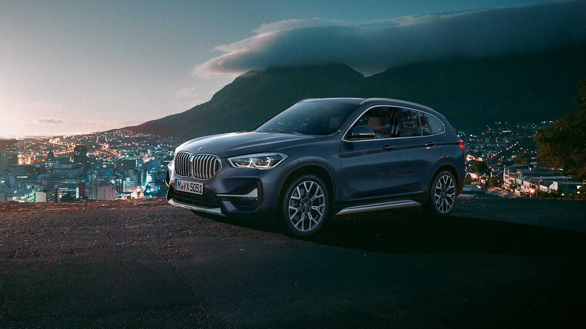 BMW X1, trojštvrťový bočný pohľad. BMW X1, trojštvrťový bočný pohľad na vozidlo stojace pred kulisami mesta.