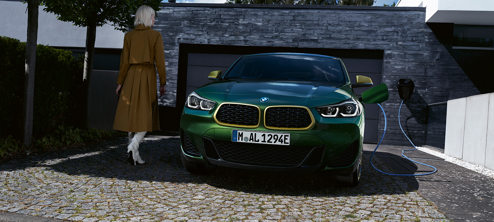 Predný pohľad BMW X2 F39 metalíza Sanremo Green Predný pohľad počas nabíjania s osobou vľavo BMW X2 F39 metalíza Sanremo Green