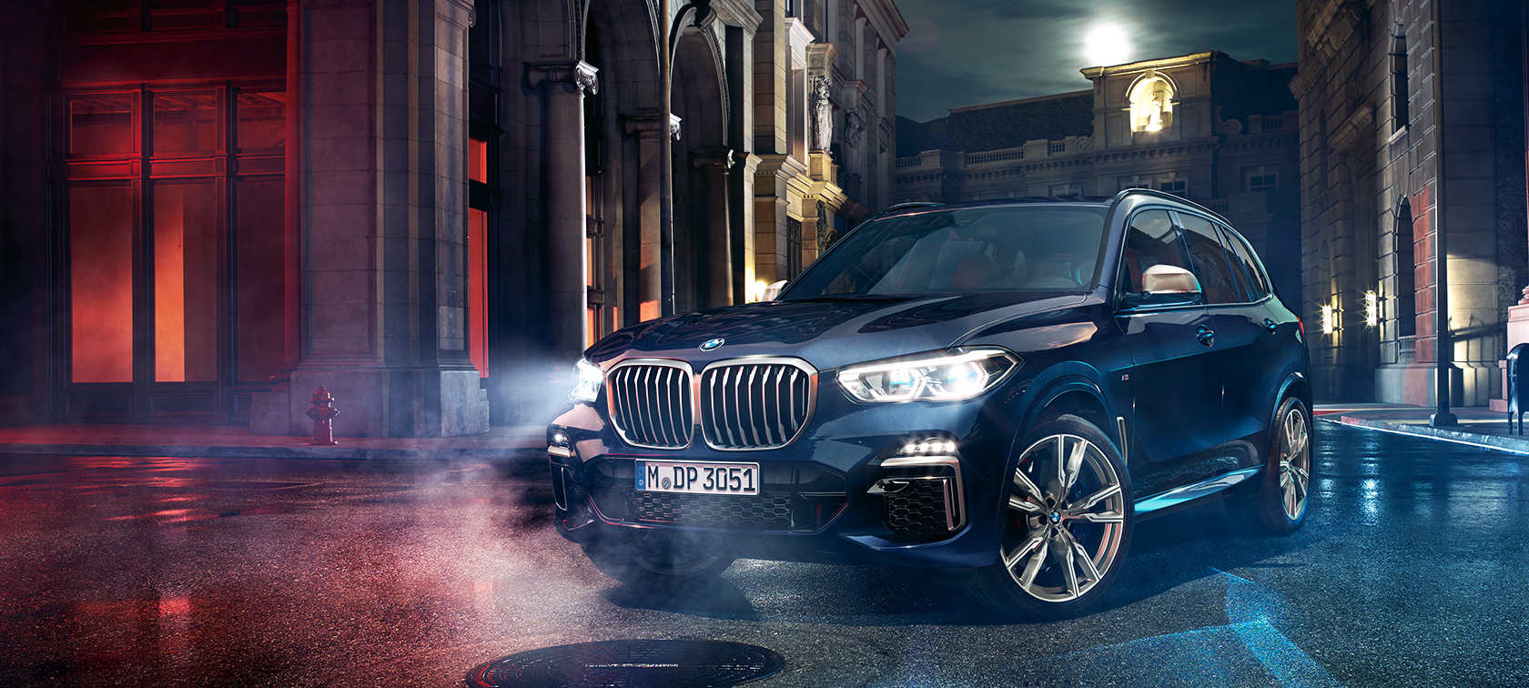 BMW X5 M50d na ceste BMW X5 M50d stojace na ceste pred pozadím nočného mesta