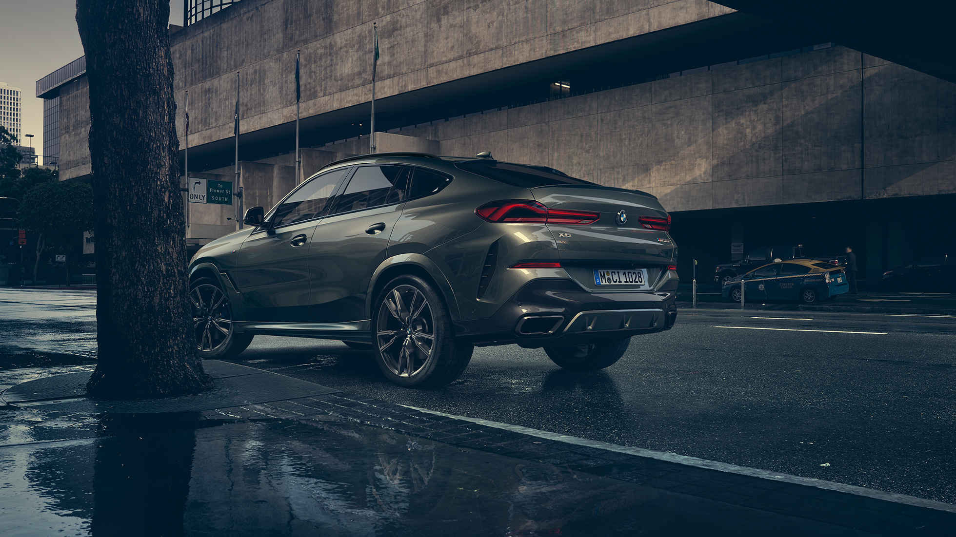BMW X6 exteriér. BMW X6, trojštvrťový zadný pohľad na vozidlo stojace pred kulisami mesta.