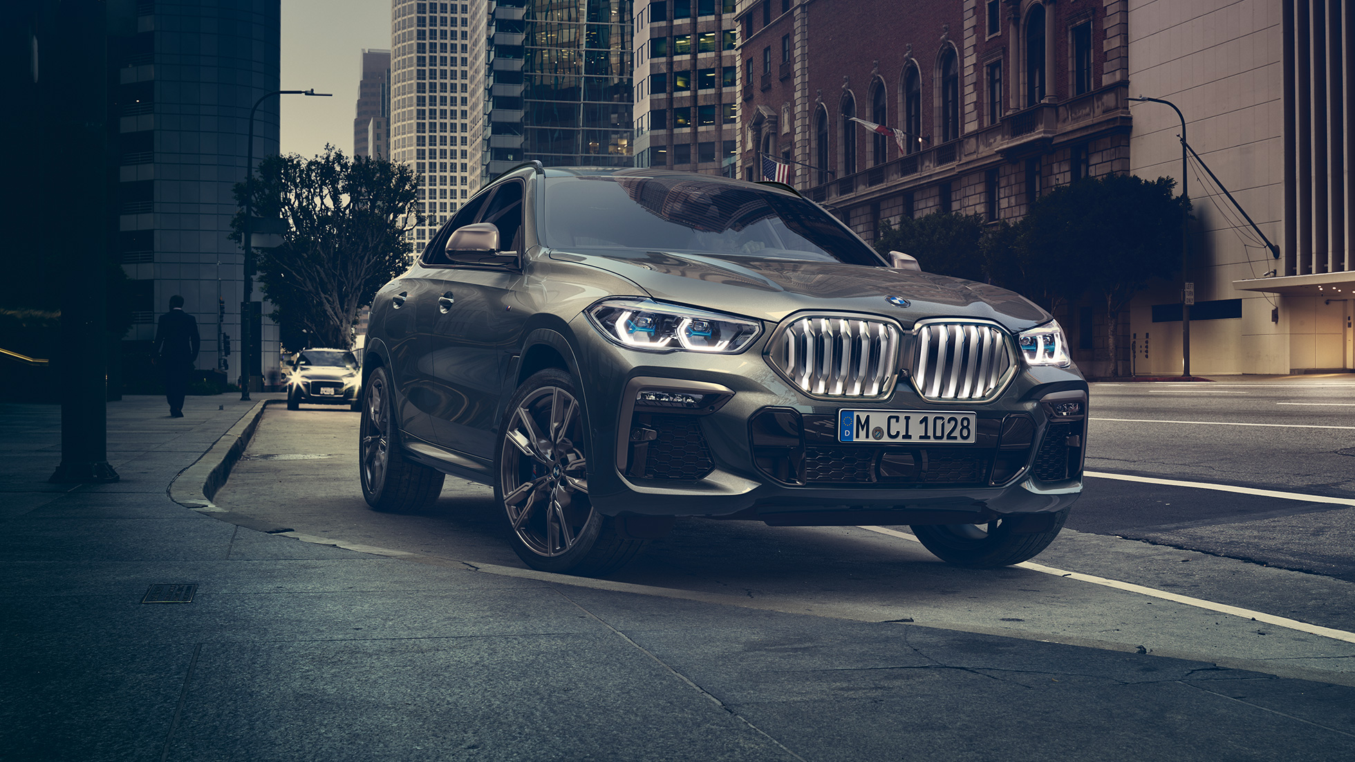 BMW X6 adaptívny M podvozok Professional BMW X6, trojštvrťový predný pohľad na vozidlo stojace pred kulisami mesta.