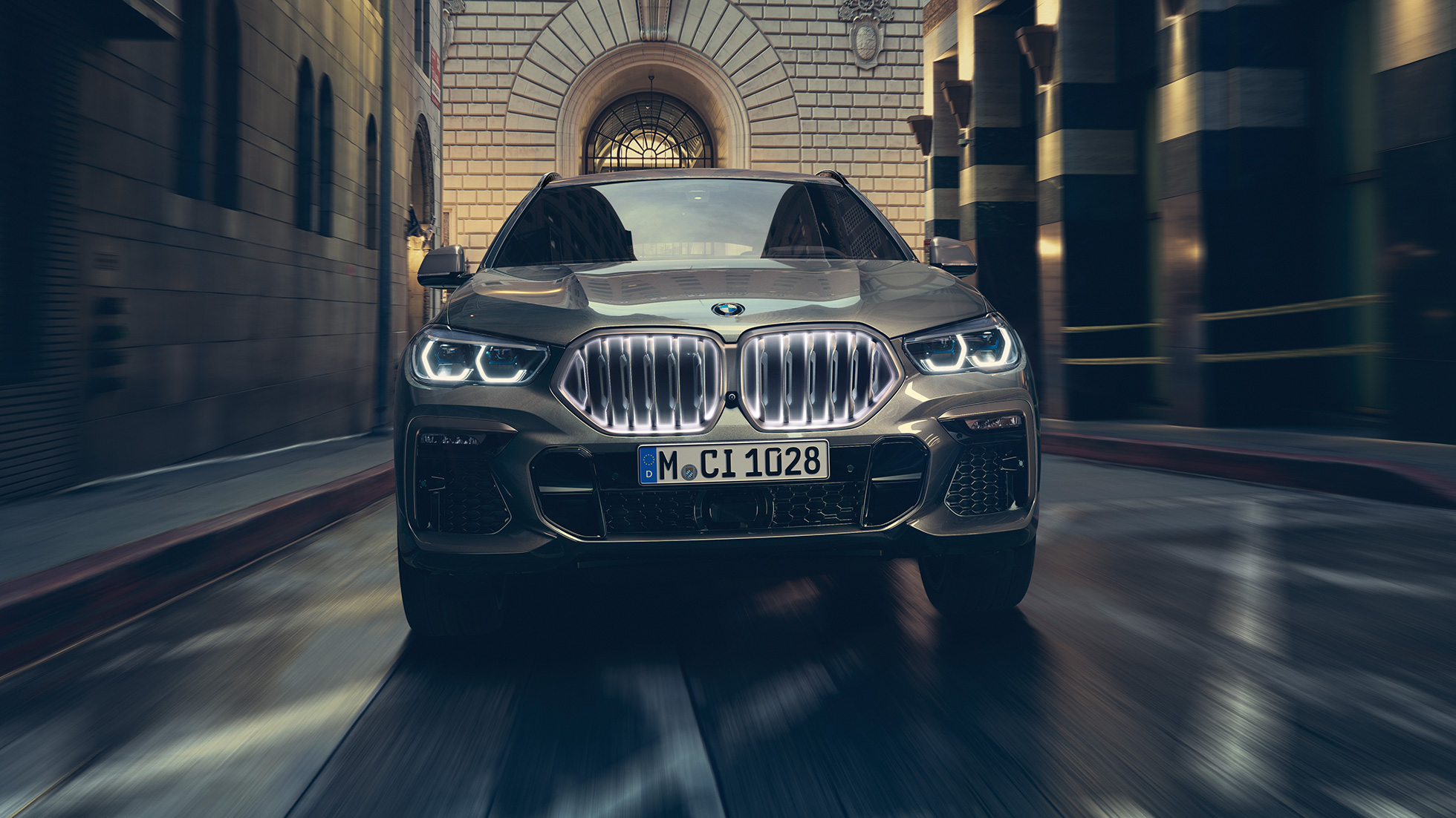 BMW X6 s BMW mriežkou chladiča Iconic Glow. BMW X6 predný pohľad na vozidlo pred kulisami mesta.