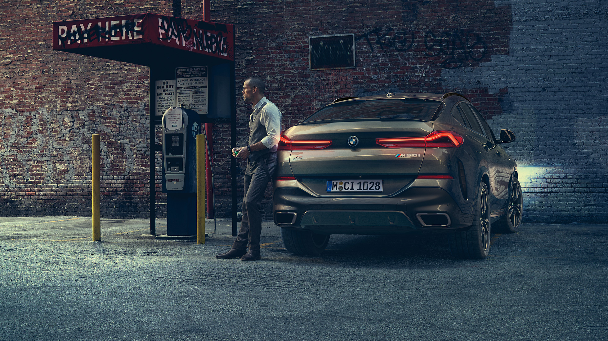 BMW X6 zadná časť. BMW X6, zadný pohľad na vozidlo pred kulisami mesta.