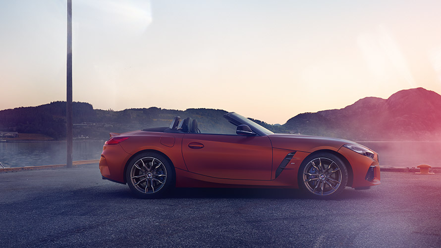 Oranžové BMW Z4 First Edition stojace v zákrute Oranžové BMW Z4 First Edition stojace v zákrute s horami v pozadí