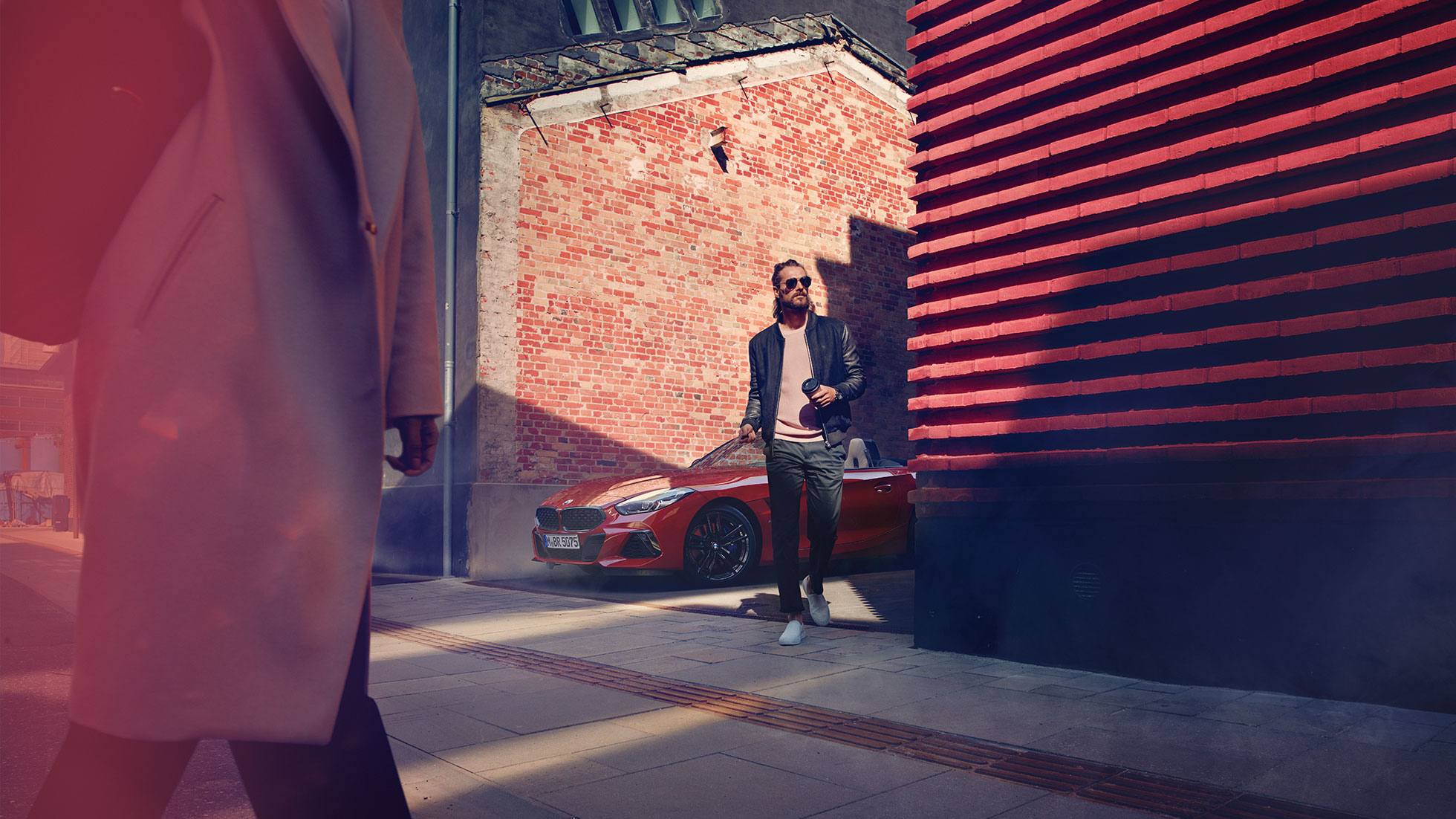 BMW Z4 Roadster v bočnej ulici Muž v bočnej ulici pred BMW Z4 Roadster