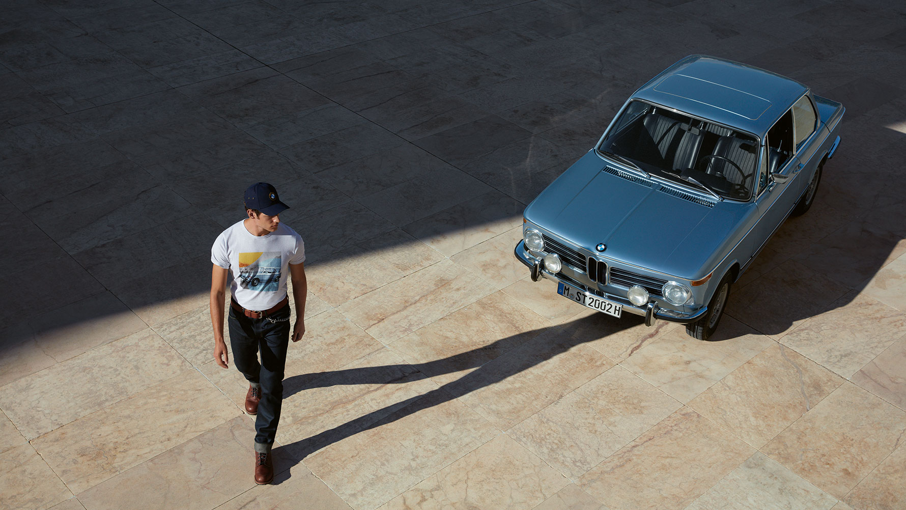 Muž v pánskom tričku BMW Classic, ktorý obdivuje klasický veterán BMW. Muž v pánskom tričku BMW Classic, ktorý obdivuje klasický veterán BMW.
