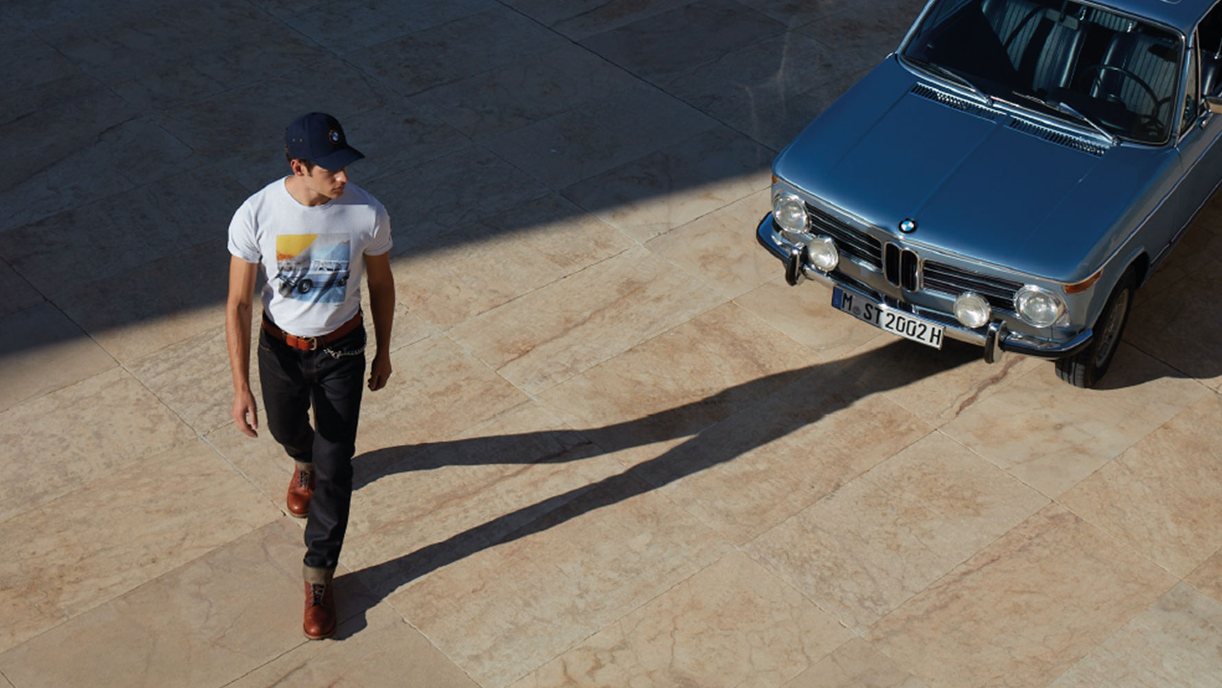 Muž v pánskom tričku BMW Classic, ktorý obdivuje klasický veterán BMW. Muž v pánskom tričku BMW Classic, ktorý obdivuje klasický veterán BMW.