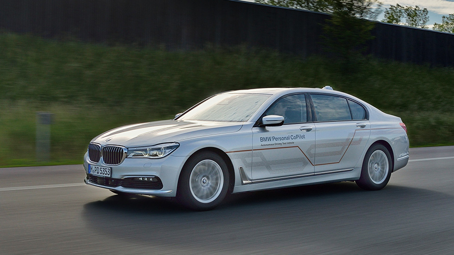 Sivé BMW radu 7 Sedan Sivé BMW radu 7 Sedan v jazde po moste s mrakodrapmi v pozadí