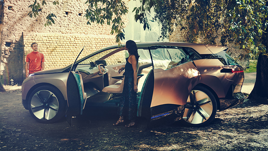 BMW Vision iNEXT zboku BMW Vision iNEXT zboku so ženou pri otvorených dverách a mužom v pozadí