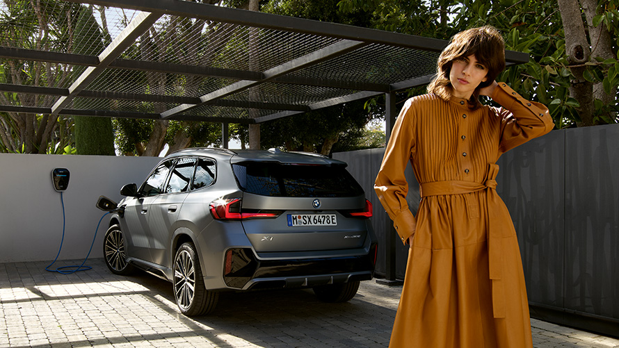BMW X1 plug-in hybrid 2022 U11 Zadný pohľad počas nabíjania s osobou BMW X1 plug-in hybrid 2022 U11 Zadný pohľad počas nabíjania s osobou