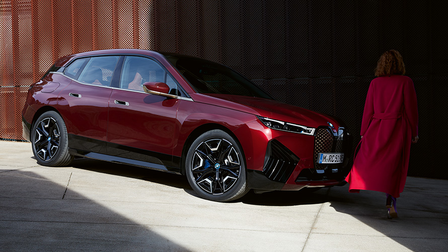 BMW Digital Key Plus BMW iX predobočný pohľad so ženou BMW Digital Key Plus BMW iX predobočný pohľad so ženou v červenom kabáte