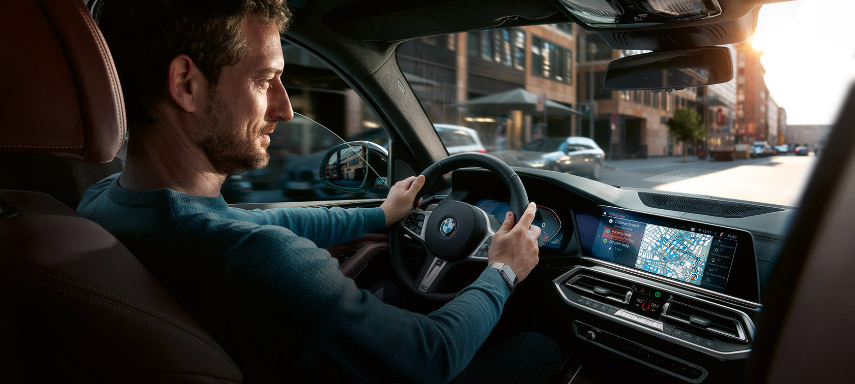 Navigácia BMW Maps Muž za volantom s navigáciou BMW Maps na iDrive displeji