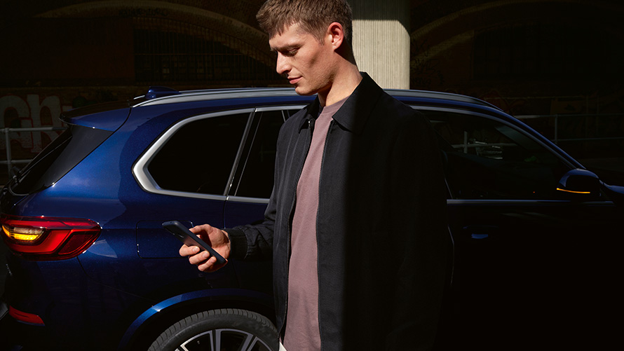 BMW Digital Key – nainštalujte až piatich používateľov BMW Digital Key inštalácia až piatich používateľov muž so smartfónom pred BMW X5