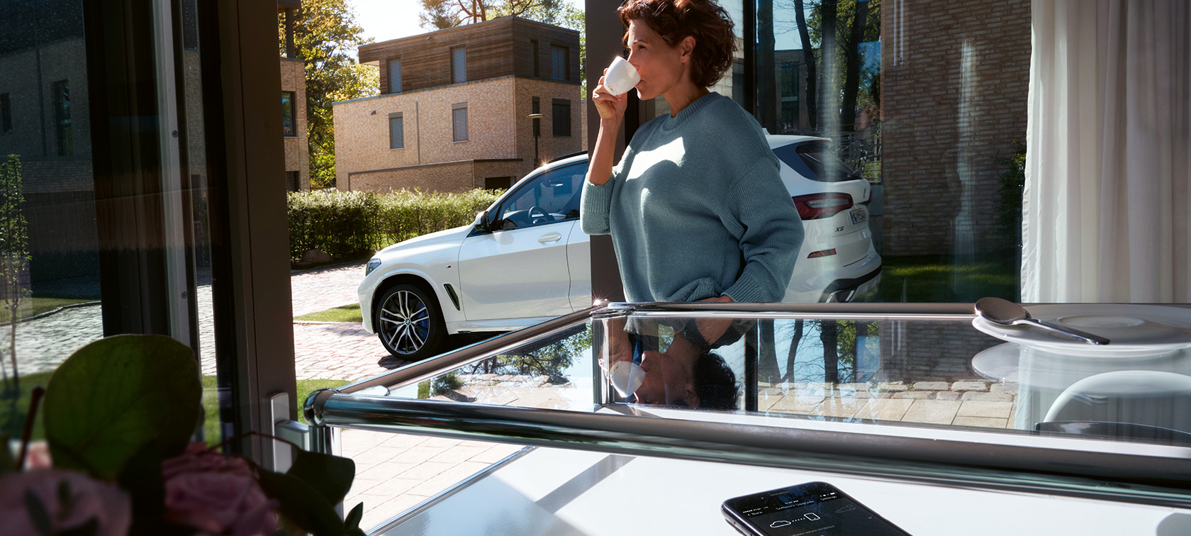 BMW Remote Software Upgrade Žena pije zo šálky kým Remote Software Upgrade aktualizuje softvér jej BMW X5