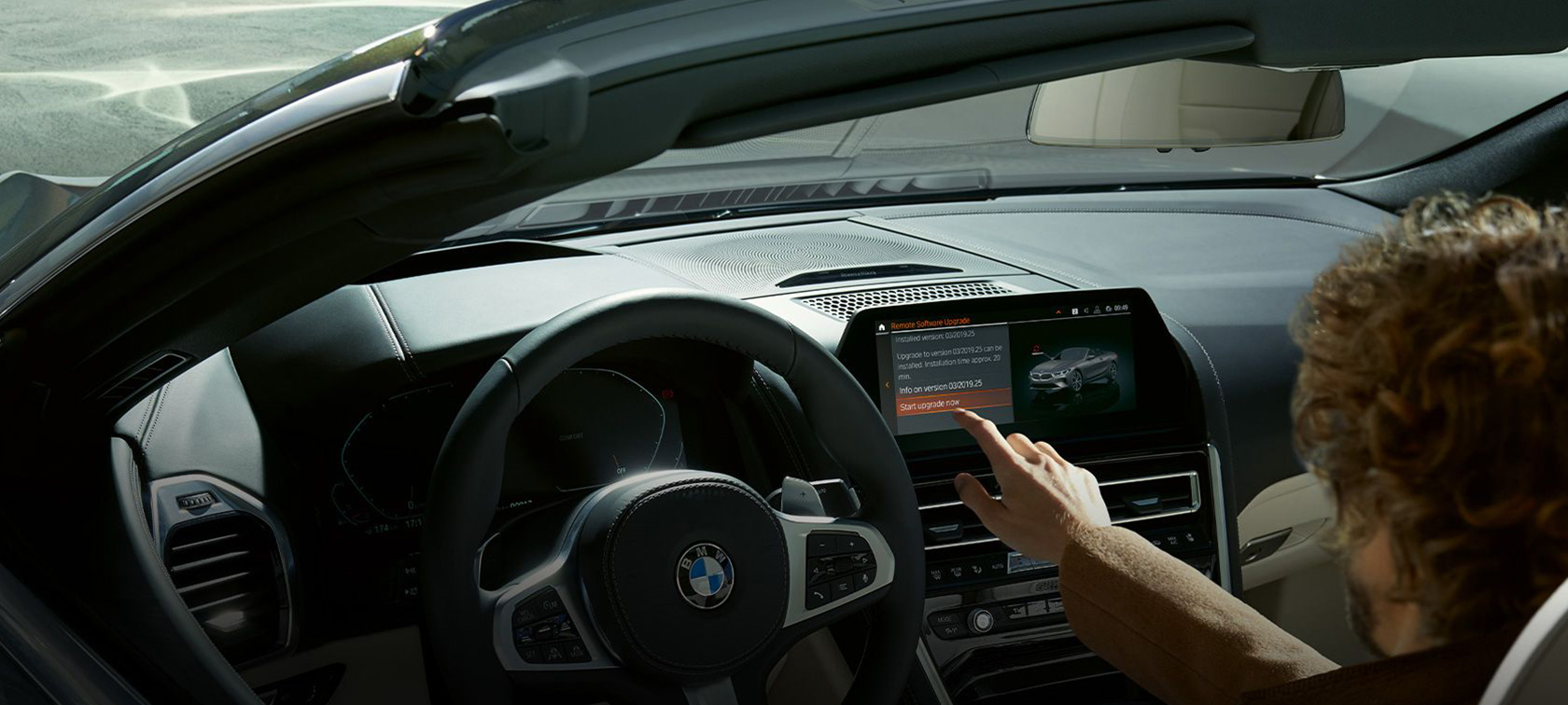 BMW Remote Software Upgrade Muž sedí v BMW a štartuje BMW Remote Software Upgrade