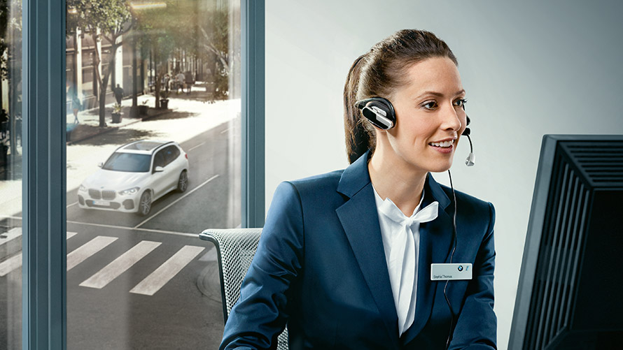 Concierge Service Concierge Service: Pracovníčka BMW sedí pred obrazovkou so slúchadlami na ušiach