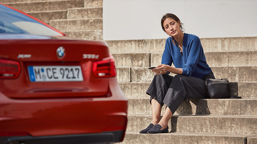 Servis a asistencia pri poruche Žena sedí pred svojím BMW a využíva Servis a asistenciu pri poruche