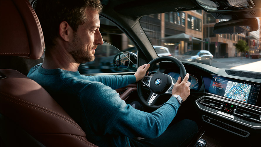 Asistent parkovacieho miesta Muž používa Asistenta parkovacieho miesta na displeji v BMW