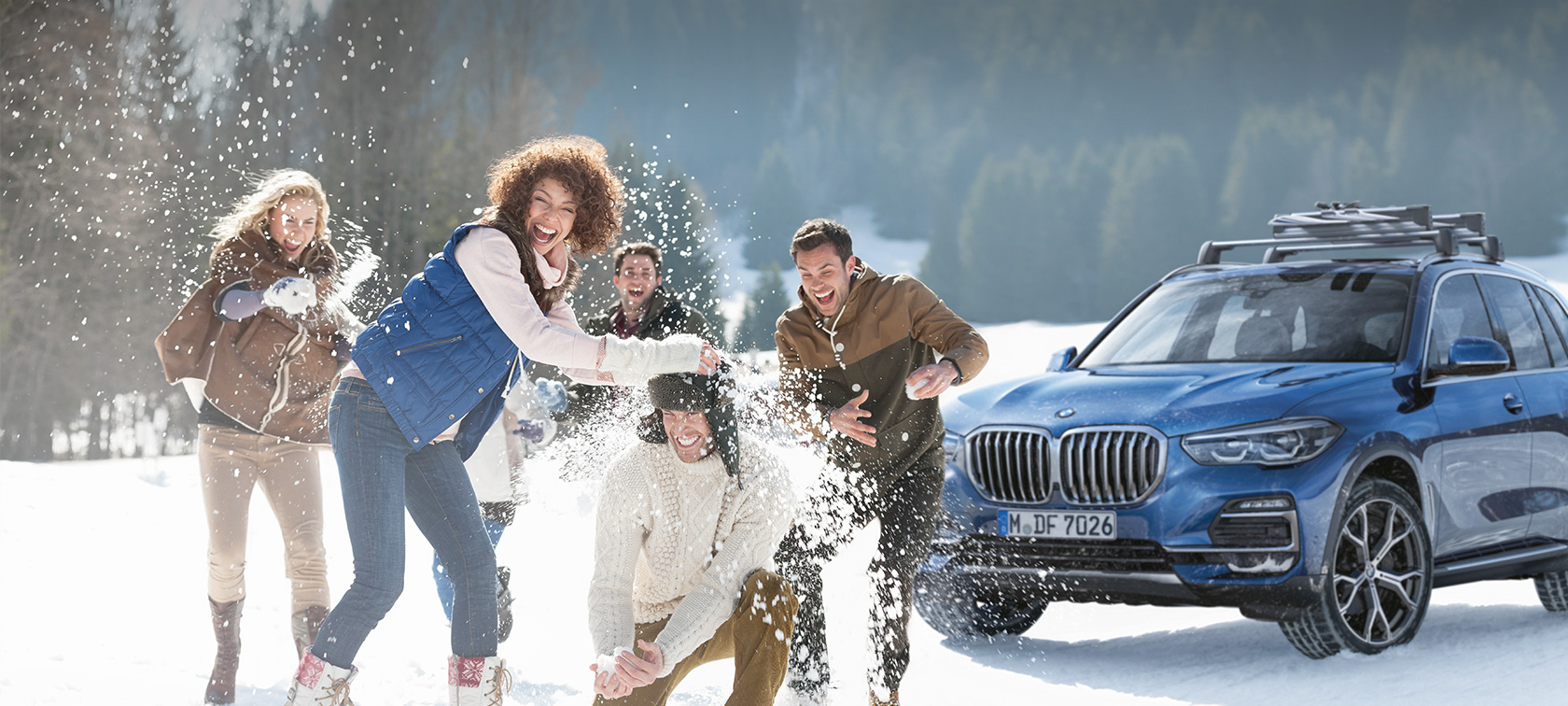 Originálne BMW príslušenstvo a BMW servis na jeseň a zimu Žena a muž, ktorí sa usmievajú v snehu pred vozidlom BMW