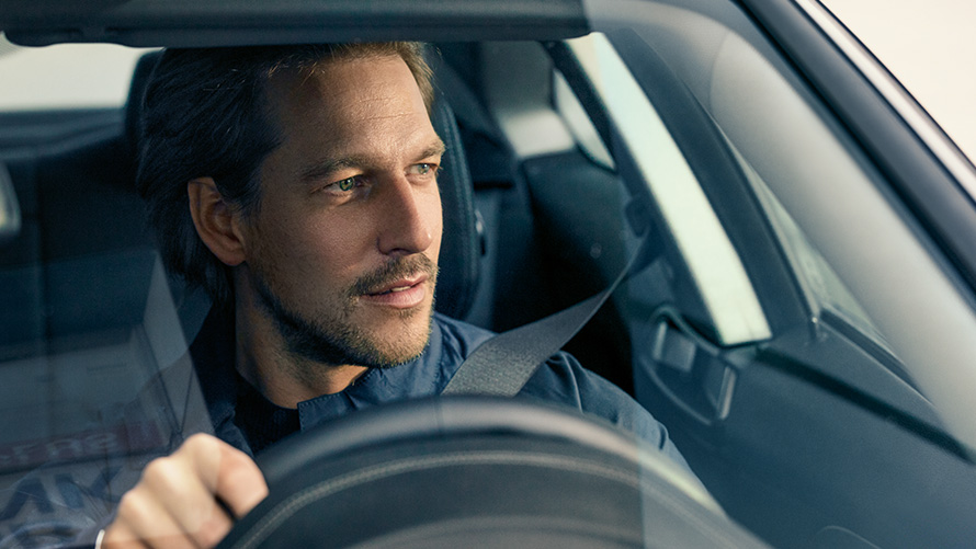 Muž šoférujúci BMW Muž šoférujúci BMW, ktorý hľadí cez čelné sklo