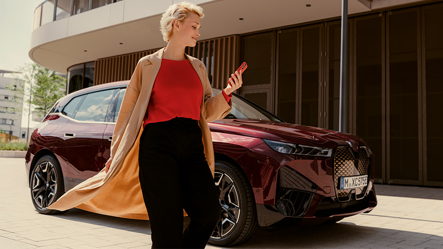 Žena so smartfónom s aplikáciou My BMW pred BMW Žena so smartfónom pred BMW