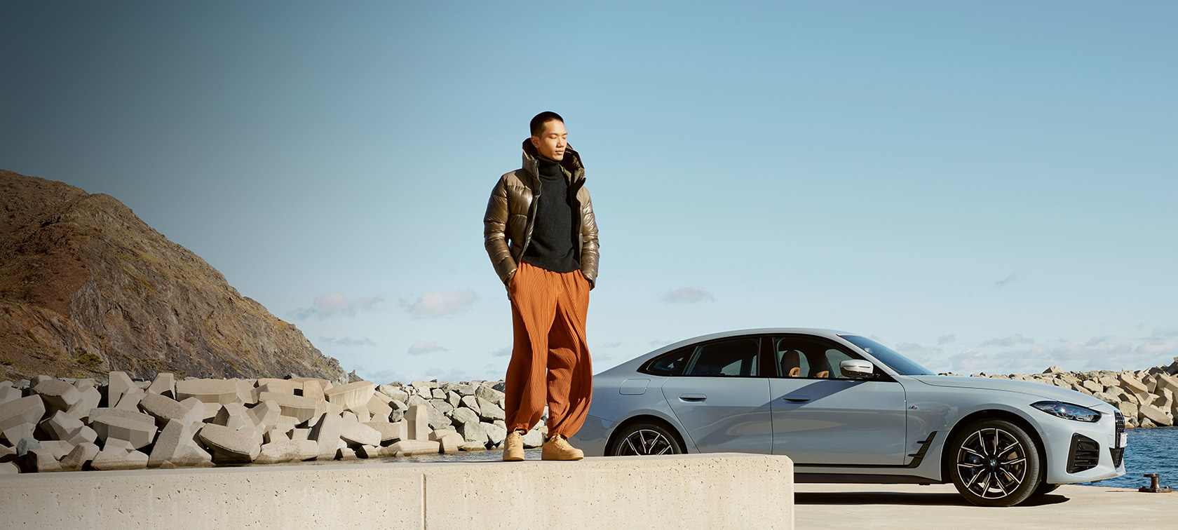 BMW Service Inclusive Muž s balíkom BMW Service Inclusive pred BMW i4 na pobreží
