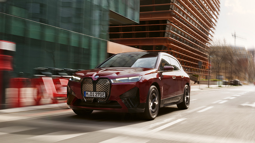 Služby BMW Teleservice, čelný pohľad z troch štvrtín na jazdiace BMW iX Služby BMW Teleservice, čelný pohľad z troch štvrtín na BMW iX jazdiace po ulici