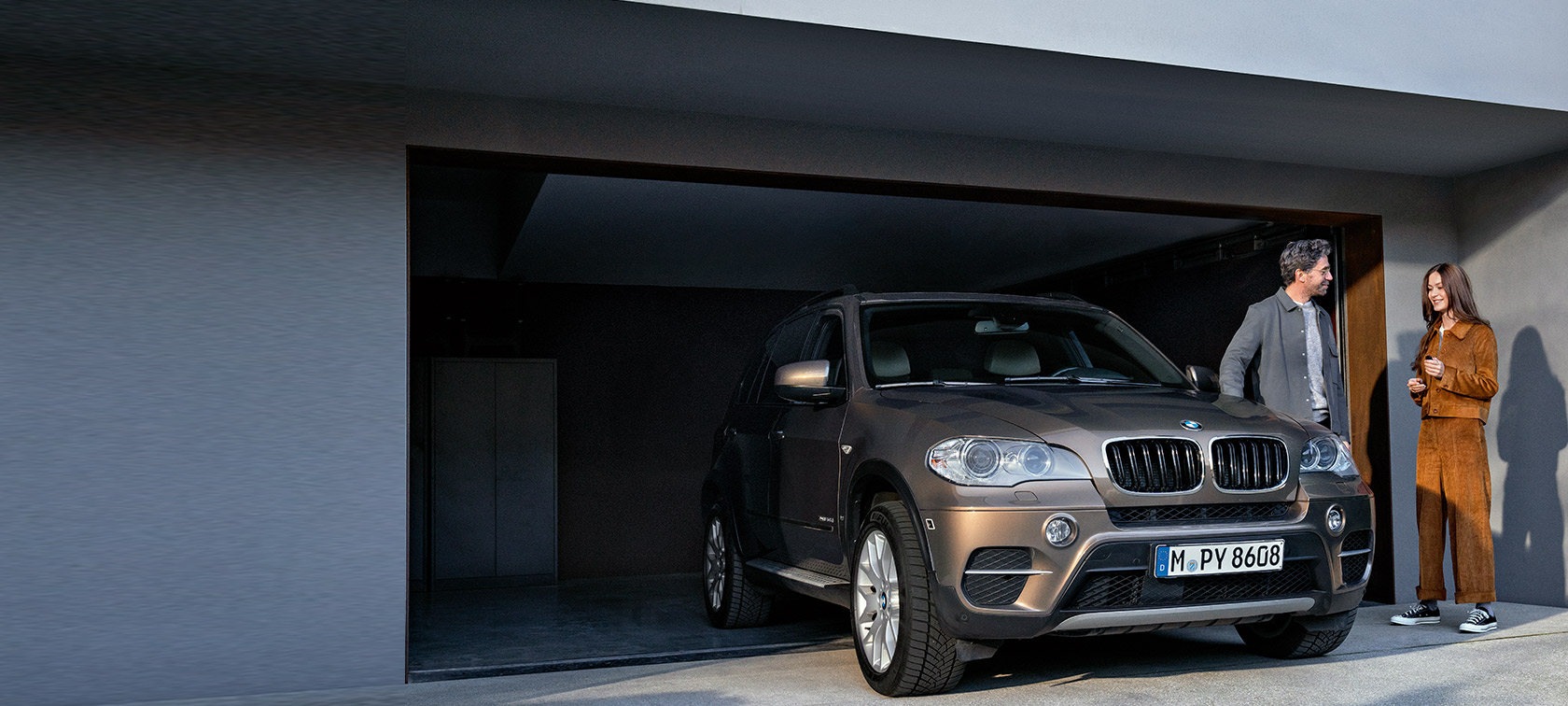 Balík BMW Value Service Balík BMW Value Service, muž a žena pred garážou s vozidlom BMW X5