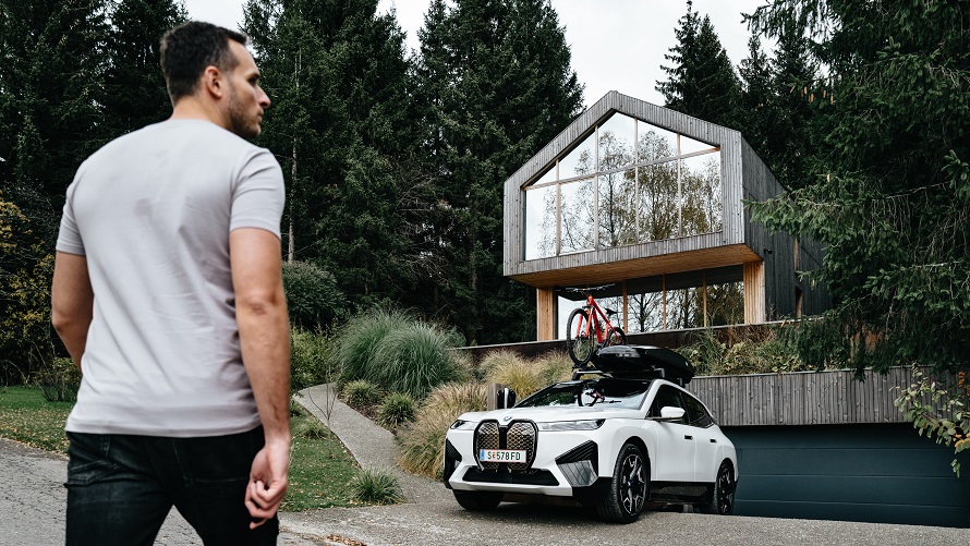 Muž ide do BMW iX pred domom. Muž ide do BMW iX pred domom.